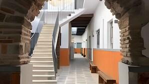A corridor with a stone archway, a staircase, and a tiled floor.