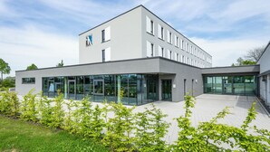 Un edificio moderno di un hotel con tetto piatto, ampie finestre in vetro e un logo sul lato.