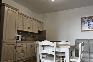 Una cucina con mobili in legno, un forno a microonde e un tavolo da pranzo con sedie.