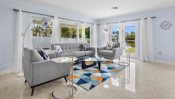 A modern living room with two grey sofas, a glass coffee table, and a colorful rug.