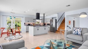 A modern kitchen with a central island, stainless steel appliances, and a tiled backsplash.