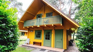 A two-story wooden cabin with a balcony, green doors, and a number '59' on the front. - Cozy Swedish group home in forest with private parking (Soest)