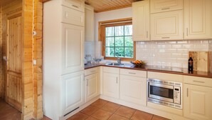 A kitchen with white cabinets, a stainless steel oven, and a window with a view of trees. - Cozy Swedish group home in forest with private parking (Soest)