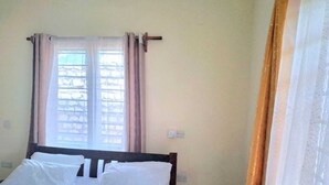 A simple, clean room with a bed, a window with curtains, and a plain wall. - Zai Homes Watamu (Watamu)