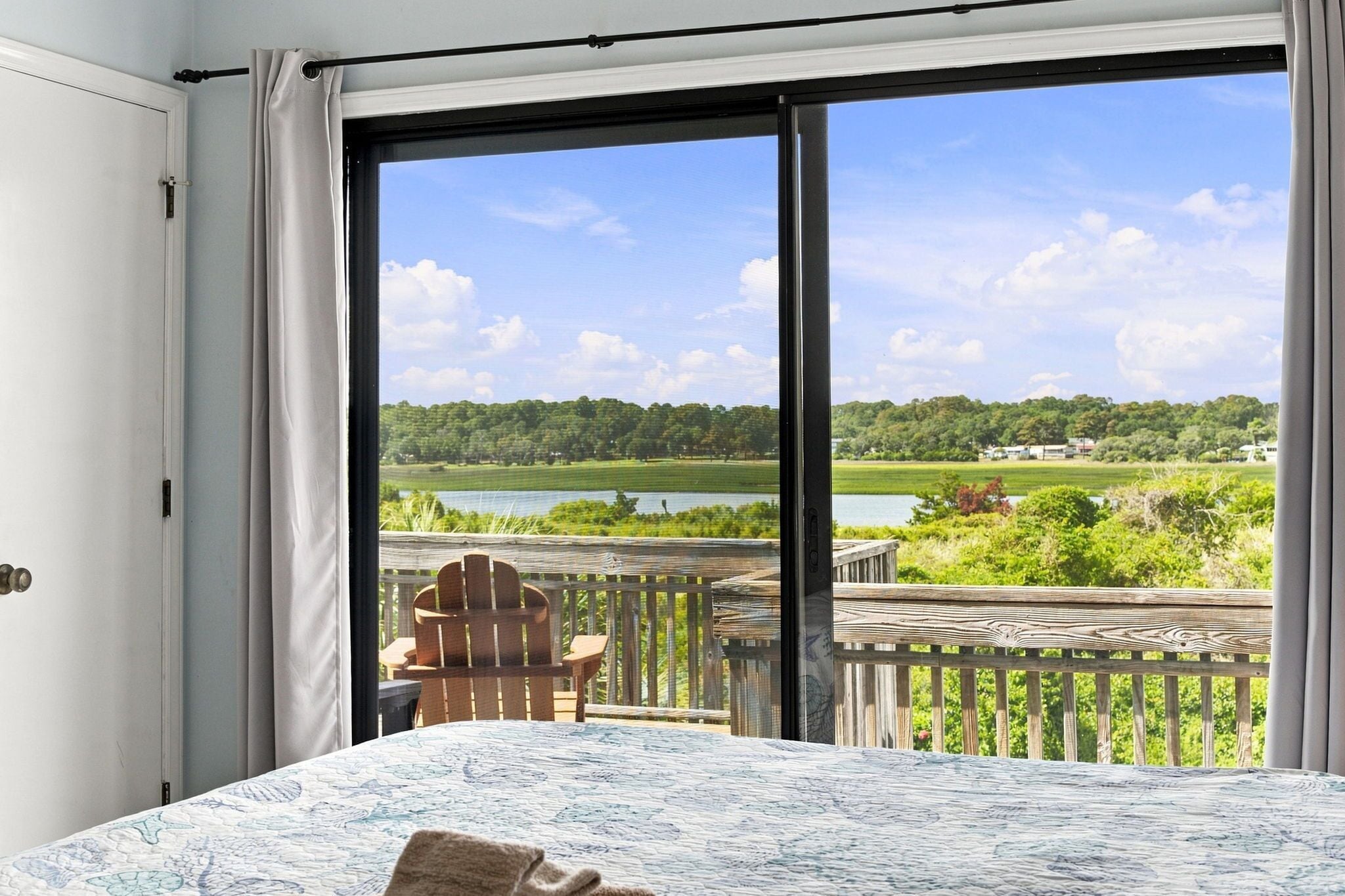 A room with a large window, a bed, and a chair.