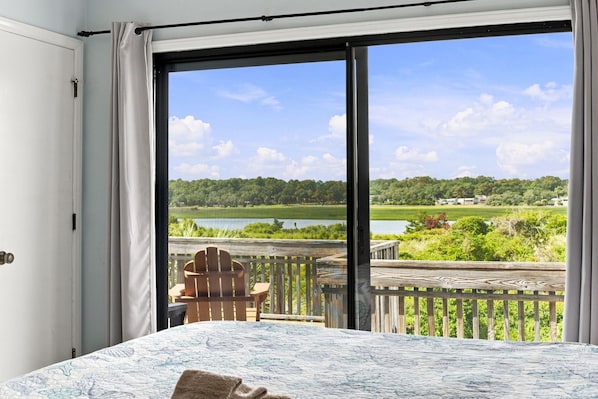 A room with a large window, a bed, and a chair.
