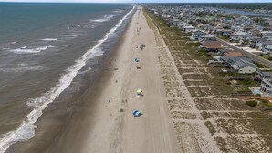 Vue aérienne d’une plage bordée de maisons.