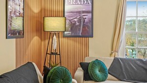 A living room with a sofa, a floor lamp, and framed pictures on the wall. - The Bristol Harbourside Apartments - Sleeps 16 (Bristol)