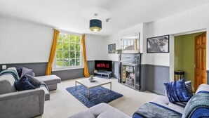 A modern living room with a sofa, a coffee table, and a fireplace. - The Bristol Harbourside Apartments - Sleeps 16 (Bristol)