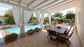 Un espacio al aire libre cubierto con piscina, muebles de patio y plantas en macetas.