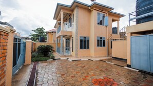 A two-story house with a balcony, a satellite dish, and a paved courtyard. - Casa Kigali (Kigali)