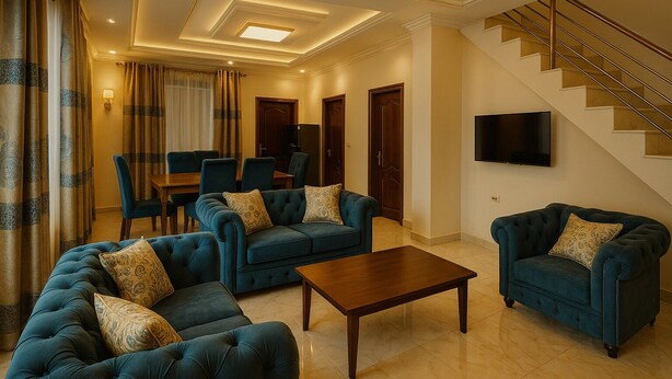A spacious living room with a sofa set, a coffee table, and a staircase leading to an upper floor. - Casa Kigali (Kigali)