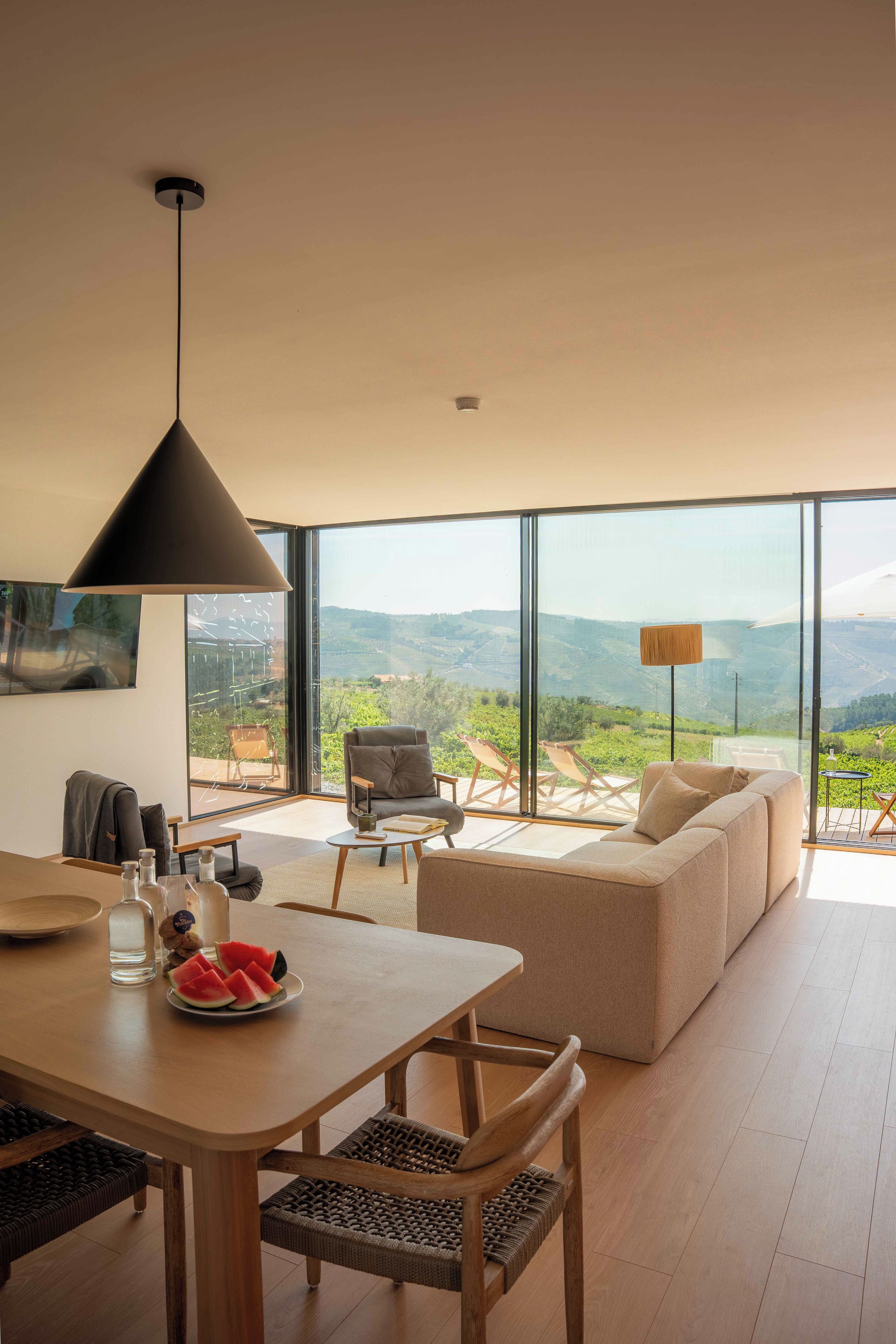 Una sala moderna con un ventanal grande, un comedor y un sofá.