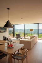 Una sala moderna con un ventanal grande, un comedor y un sofá.