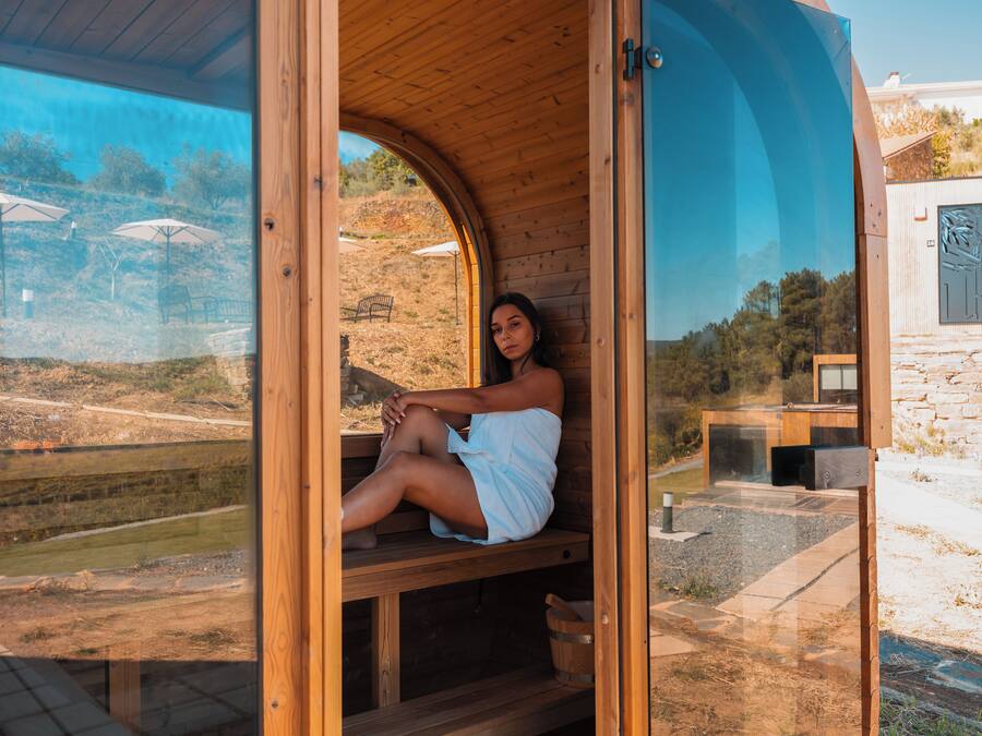 Uma sauna de madeira com vista para um jardim ajardinado e uma parede de pedra.