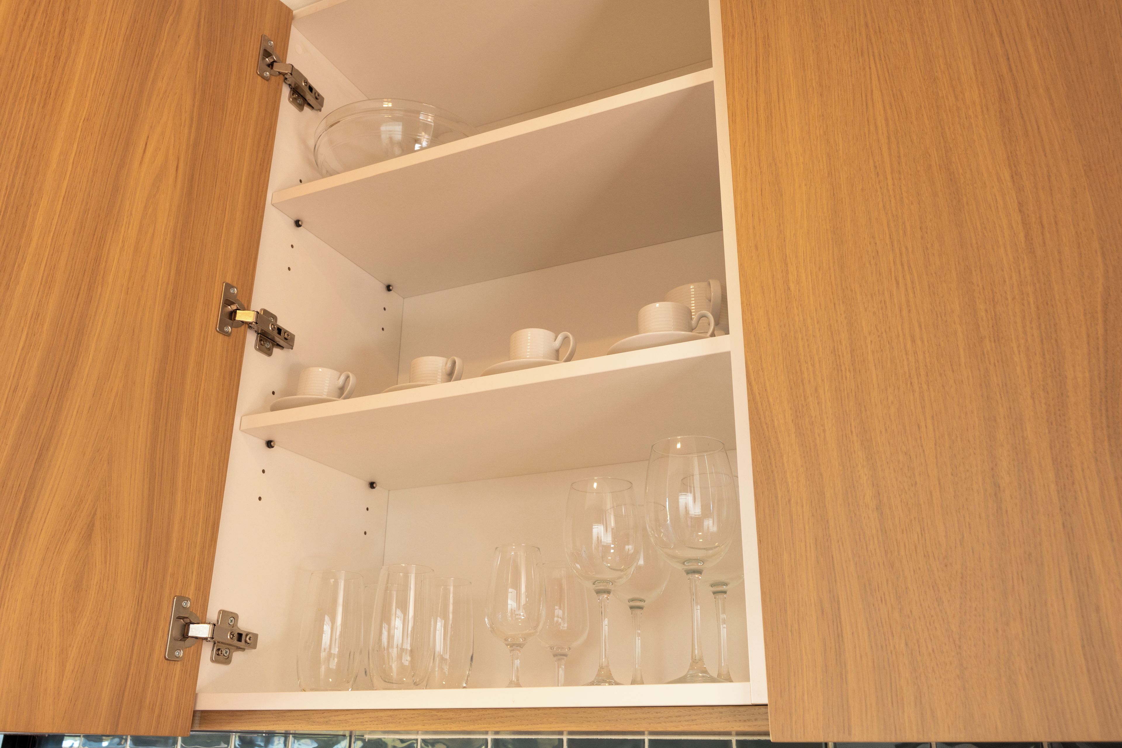 A kitchen cabinet with three shelves, each holding different items.