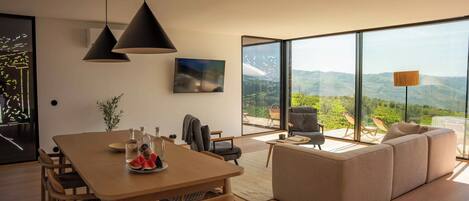 Una sala moderna con comedor, ventanas amplias y vistas al campo.