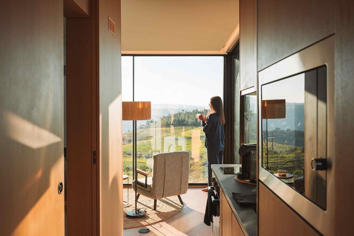 Una habitación con un ventanal grande, una silla, una mesa y una máquina de café.