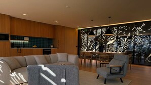 A modern living room with a sectional sofa, a dining area, and a kitchen with wooden cabinets and a backsplash. - Five Sabrosa Senses (Sabrosa)