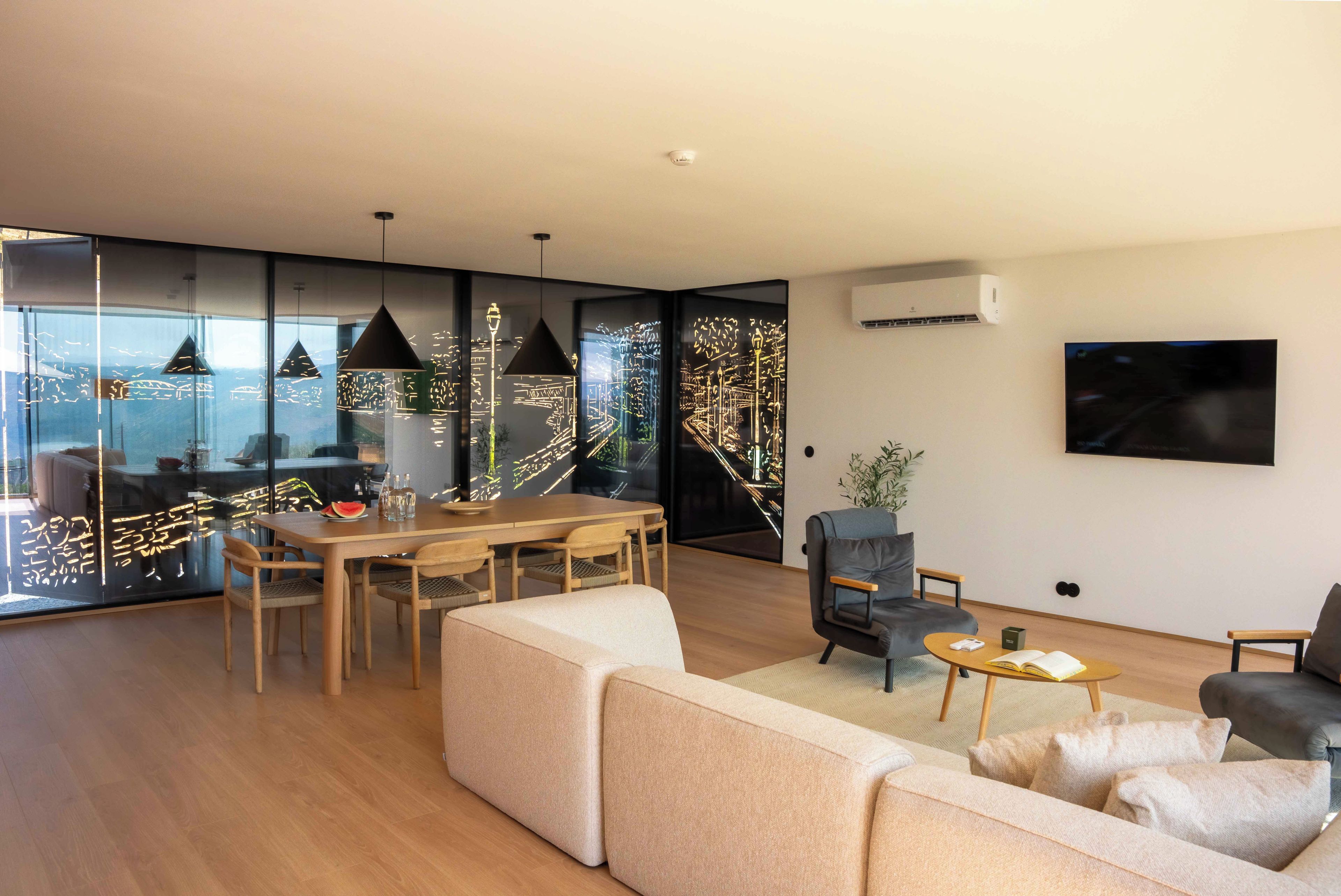 A modern living room with a dining area, large windows, and a view of the city.