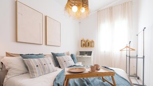 A neatly arranged bedroom with a bed, bedside table, and a hanging light fixture.