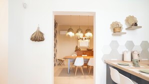 A modern kitchen with a wooden table, white chairs, and hanging pendant lights.