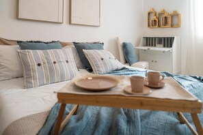 A neatly made bed with striped pillows, a bedside table with a lamp, and a wall with framed artwork.