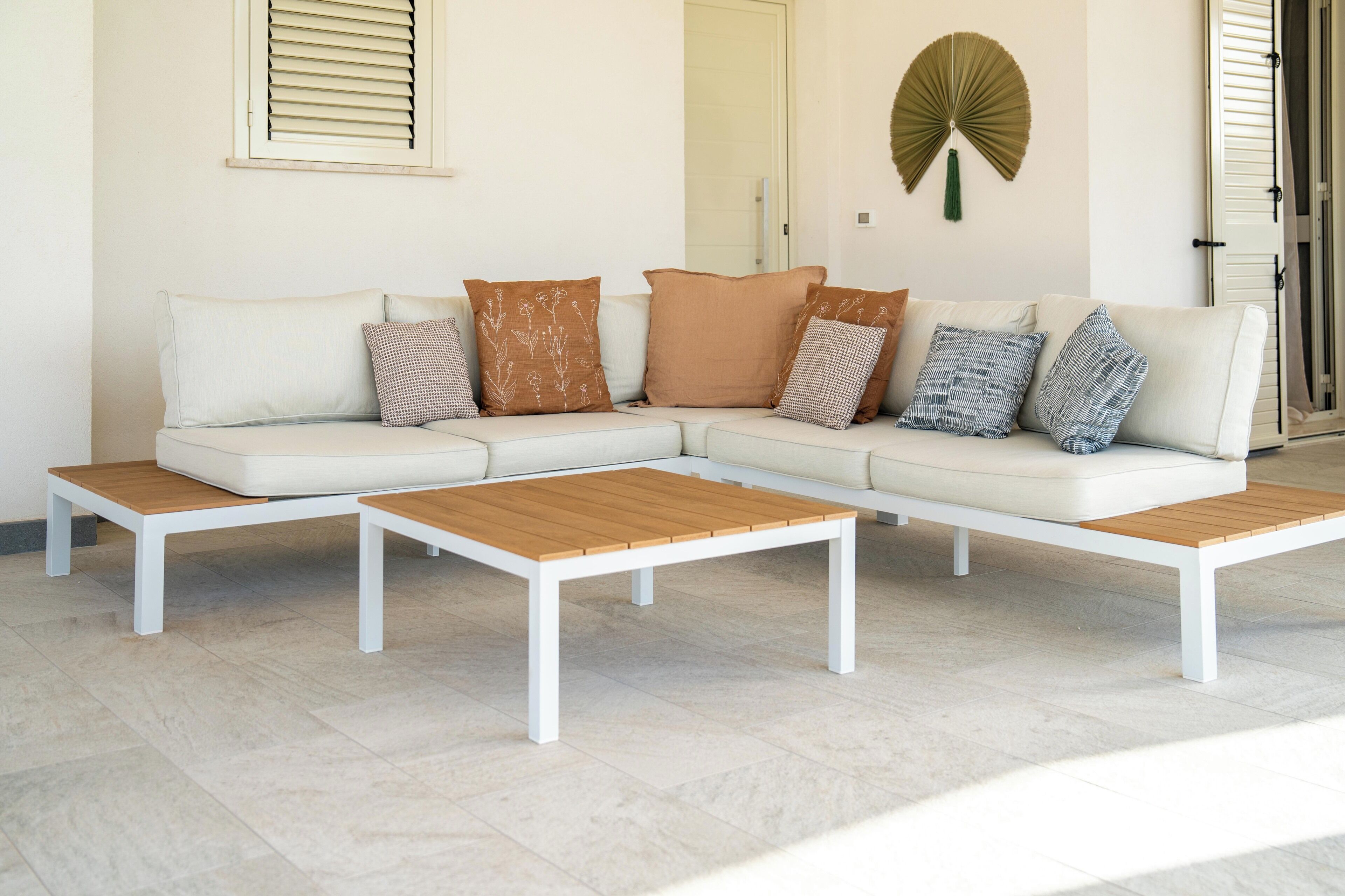 A modern living room with a white sectional sofa, two wooden coffee tables, and decorative pillows.
