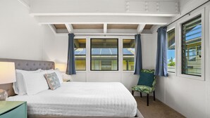 Un dormitorio con cama, una silla, una mesita de noche y un ventanal con cortinas.