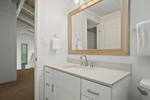 Une salle de bain avec un lavabo blanc, un miroir avec un cadre en bois et un porte-serviettes.