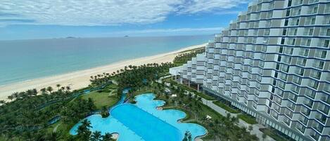 Un hotel con un amplio espacio de piscina, vistas a la playa y un diseño de edificio moderno.