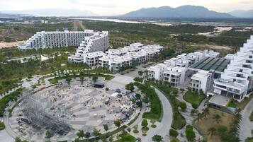 Un complex residencial modern amb diversos edificis, un espai central obert amb seients i una vista d'un aeroport i muntanyes a la distància.