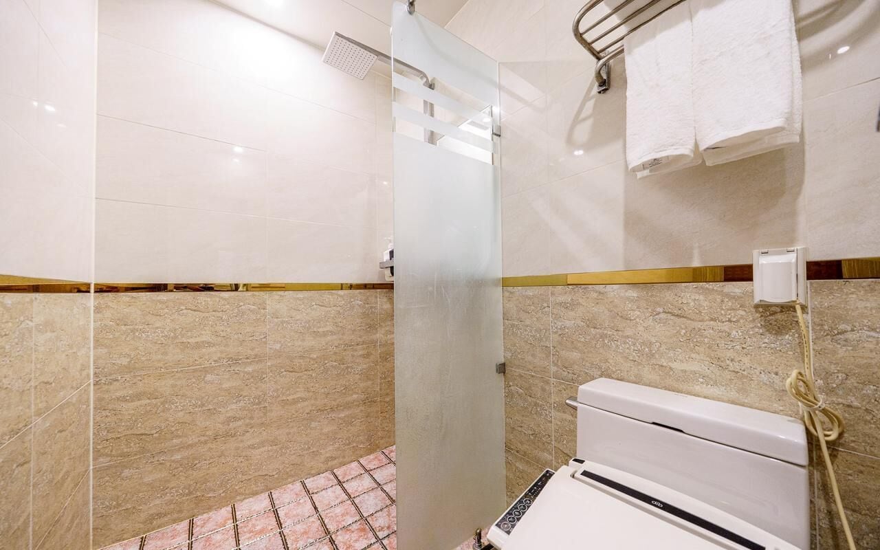 A bathroom with a shower, a toilet, and a towel rack.
