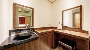 A bathroom with a wooden vanity, a sink with a decorative basin, and two mirrors with wooden frames. - Jardin Hotel (Seoul)