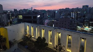Une vue sur une ville au crépuscule, avec des bâtiments illuminés et un ciel dégagé.