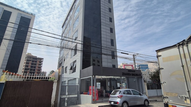 A modern building with a glass facade, a visible storefront, and a parked car in front.