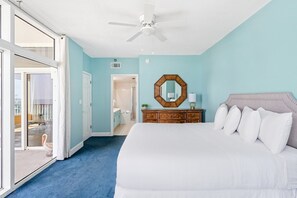 A bedroom with a large bed, a ceiling fan, a wooden dresser, and a mirror on the wall. - Beach Front, Private Balcony with Sunset Views (Destin)