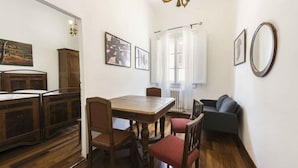 A dining area with a wooden table and chairs, a sofa, and artwork on the walls.