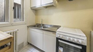A kitchen with white cabinets, a stainless steel sink, and a white stove.