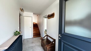 A hallway with a radiator, a bench, and a wooden staircase leading to another room.