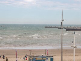 A beach with a lifeguard tower, a pier, and a lighthouse in the background.