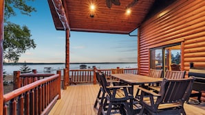 A wooden deck with a table and chairs, overlooking a body of water.
