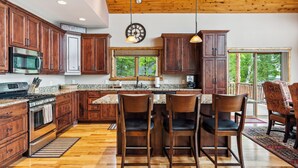 A spacious kitchen with wooden cabinets, a granite countertop, and a large island with bar stools.