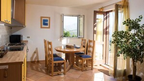 A kitchen with a stove, sink, and dining area with chairs and a table.