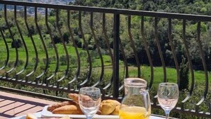 A table set outdoors with food and drinks, overlooking a mountainous landscape.