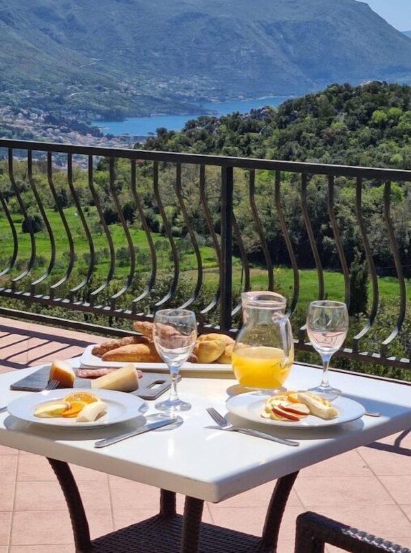 Mesa al aire libre con comida y bebidas, con vistas a un paisaje montañoso.