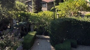 Un jardí amb un camí de grava, testos ben tallats i una varietat de plantes.