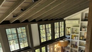 Àmplia zona d'estar amb un gran finestral, un sofà, una taula de centre i una biblioteca.