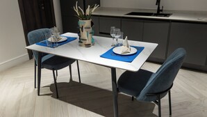 A dining table set with blue placemats, white plates, and clear glassware. - The VVS Apartments - Studio Apartment with Balcony (Accra)