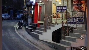 Un hotel con un cartello ben visibile 'HOTEL', una scala che conduce all'ingresso e un cartello 'GEETA HOME STAY' sottostante.